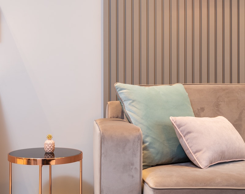 Ein elegantes Sofa aus Samt in Pastellfarben, daneben steht ein moderner Couchtisch